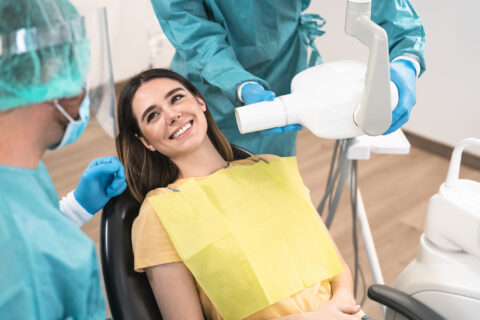dentist operating young smiling woman in dental clinic