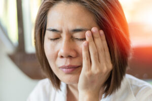 A woman touching her face as she has terrible tooth pain in Atlanta, GA 