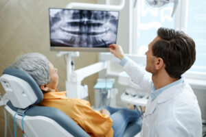 The dentist with x-ray explaining about bone grafting for dental Implants in Atlanta oral surgery, GA.