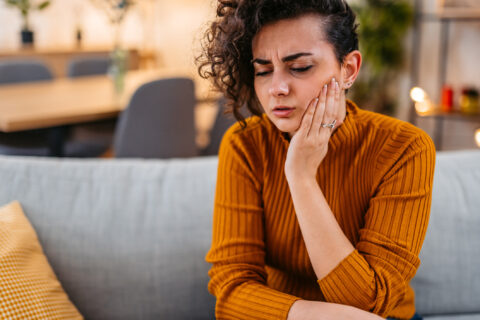 Woman holding the side of her cheek dealing with a toothache Having Toothache