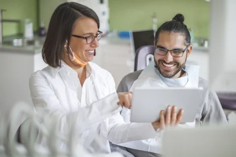 Dentist reviewing tooth extraction details on a tablet with a patient