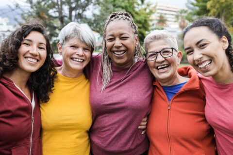 A group of five women in Atlanta, GA, smiles in a park, and their dentures are visible