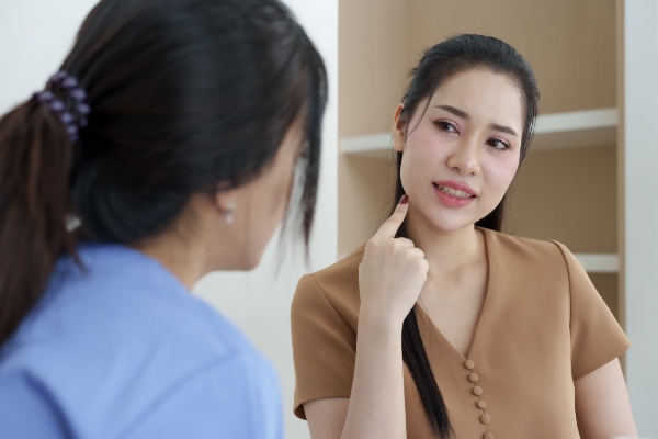 Woman explaining facial pain to oral surgeon